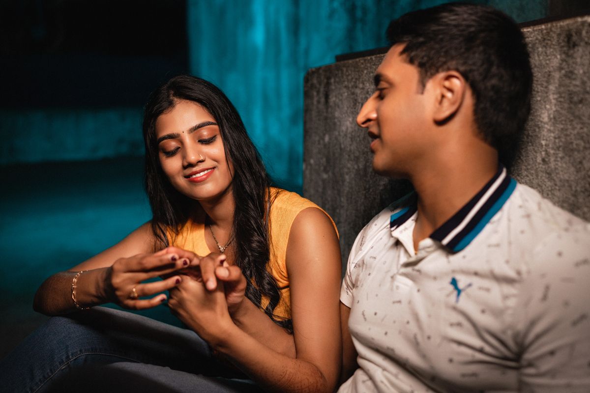 Couple sharing intimate moments in a dimly lit room with blue lighting.