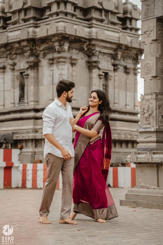 A couple shares a playful moment among ancient stone temple architecture.