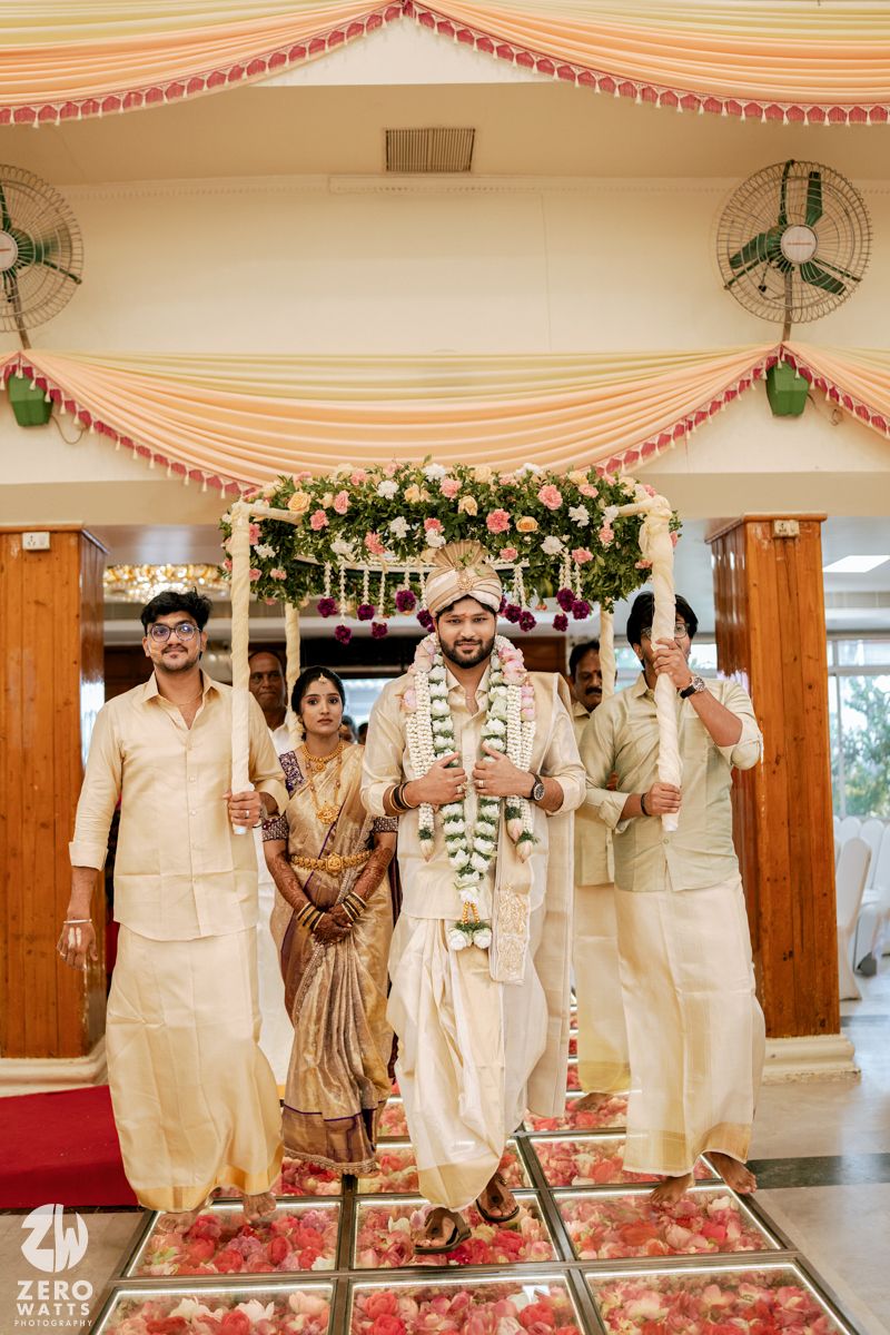 Wedding celebration in a decorated hall with cream drapes and floral arrangements.