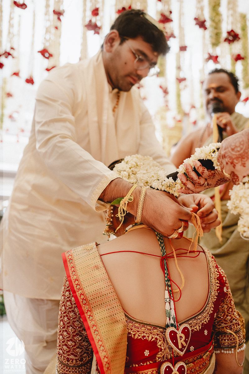 A close-up view of traditional Indian bridal attire showing intricate red and gold embroidery details on the back.