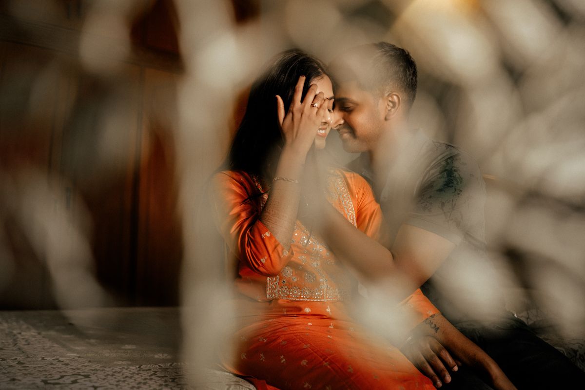 Intimate moment captured through soft focus with orange tones and bokeh effects.