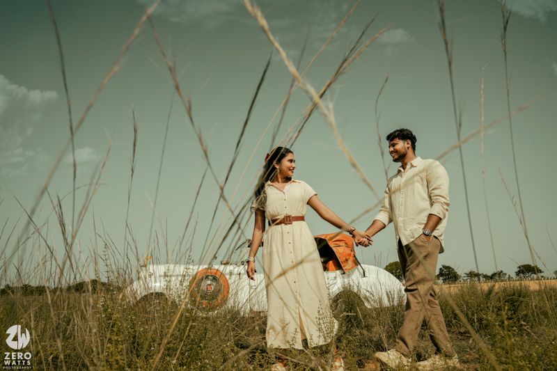 Couple enjoying a romantic moment in a field with tall grass and a dreamy atmosphere.