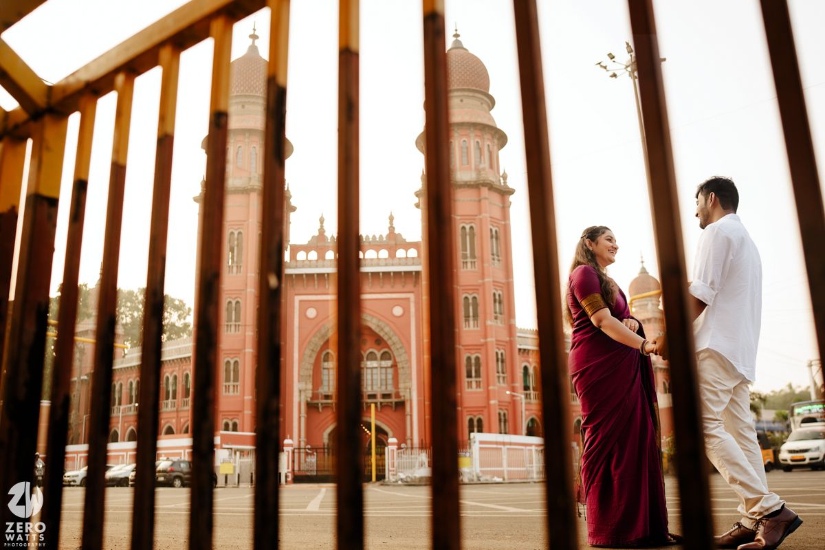 Romantic couple photoshoot at a grand historic building during golden hour with dramatic architectural backdrop.
