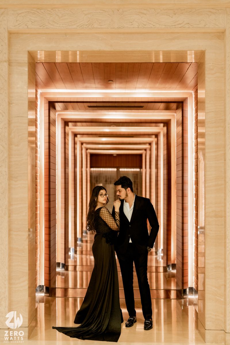 A couple poses in an elegant hallway with mirrored walls creating an infinity effect.