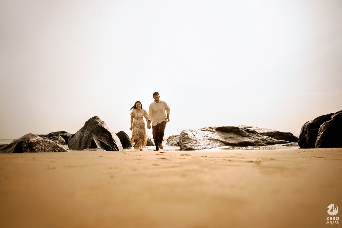 Silhouettes of people walking along a misty beach shoreline at dusk.