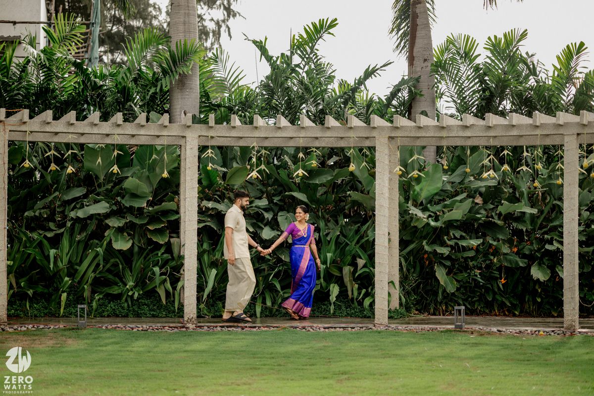 A white pergola structure with lush tropical greenery and hanging decorations creates an elegant outdoor setting.