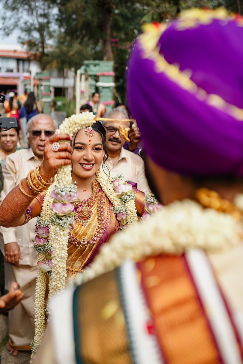 Joyful wedding celebration with guests dancing and celebrating in traditional Indian attire with floral garlands.