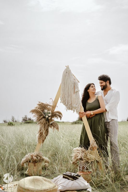 A romantic outdoor picnic setup with pampas grass decor and neutral tones in a grassy field.