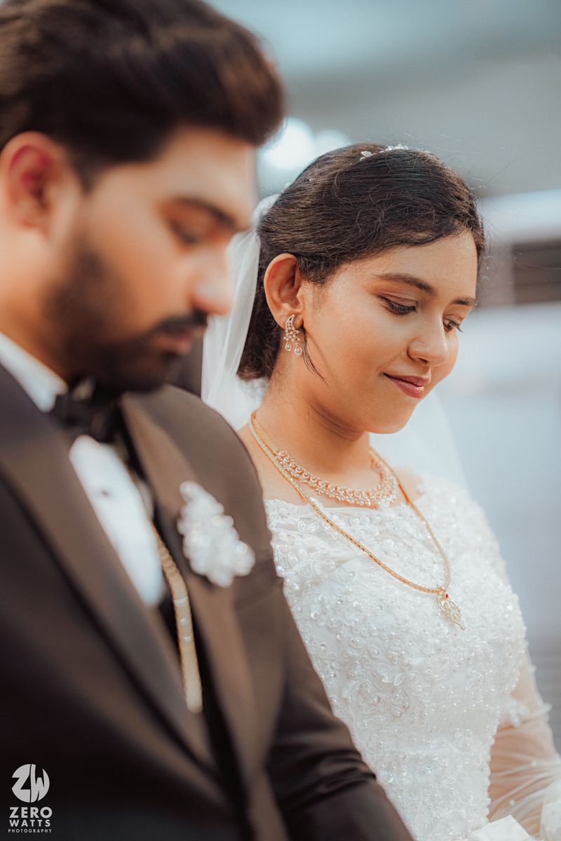 A romantic wedding moment captured in soft lighting showing the couple in elegant white dress and black suit.