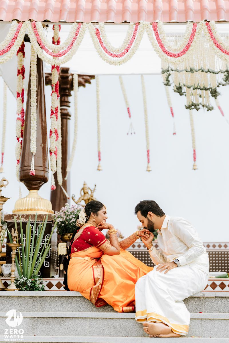 South Indian bride and groom sharing intimate moment seated at traditional wedding mandap.