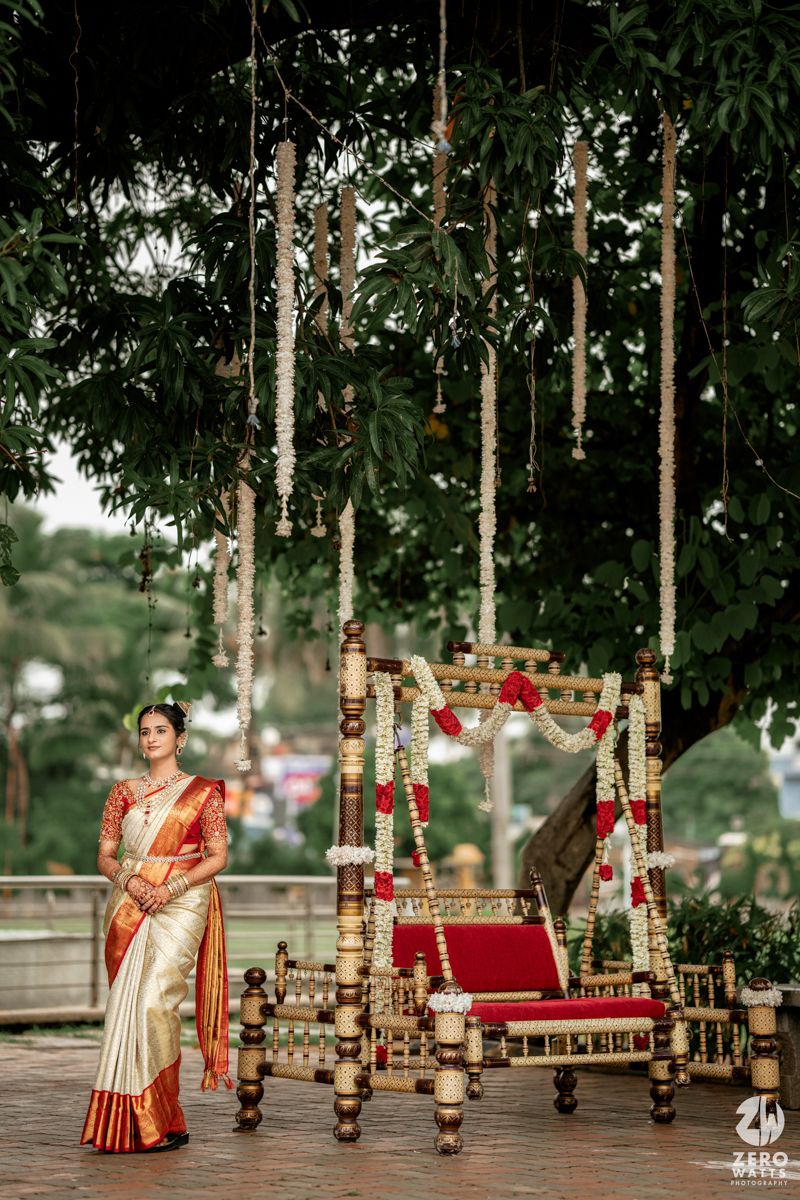 Traditional Indian wedding ceremony setup with decorated bamboo poles and red accents in an outdoor garden setting.