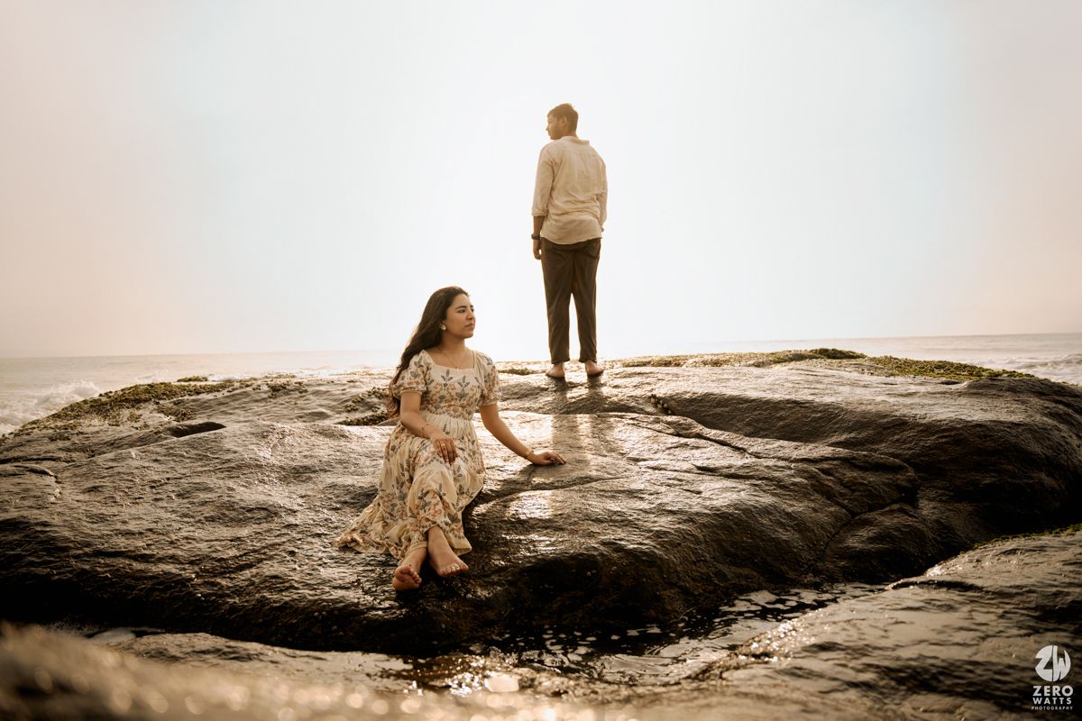 Silhouetted figures exploring rocky coastal formations during golden hour.