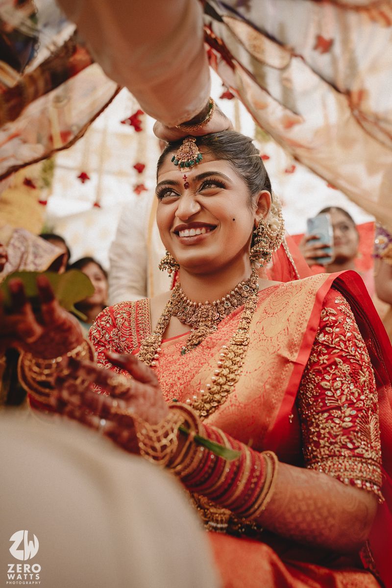 Traditional Indian bride wearing red and gold saree with ornate jewelry and mehndi during wedding ceremony preparations.
