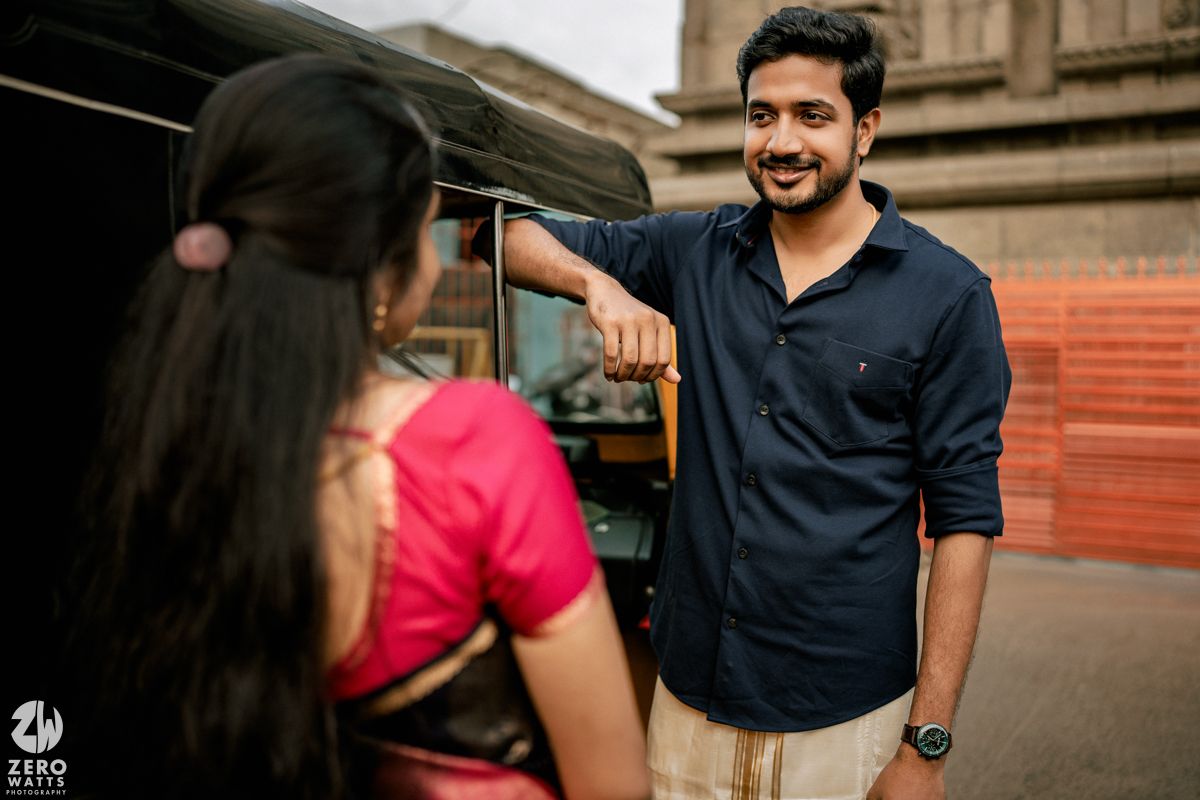 A couple in contrasting navy and red outfits sharing a candid moment during an outdoor photoshoot.