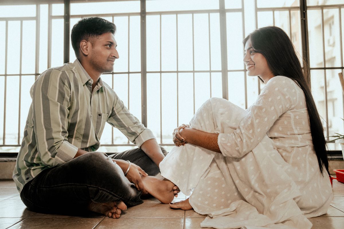 People sitting on a white floor against railings in casual conversation.