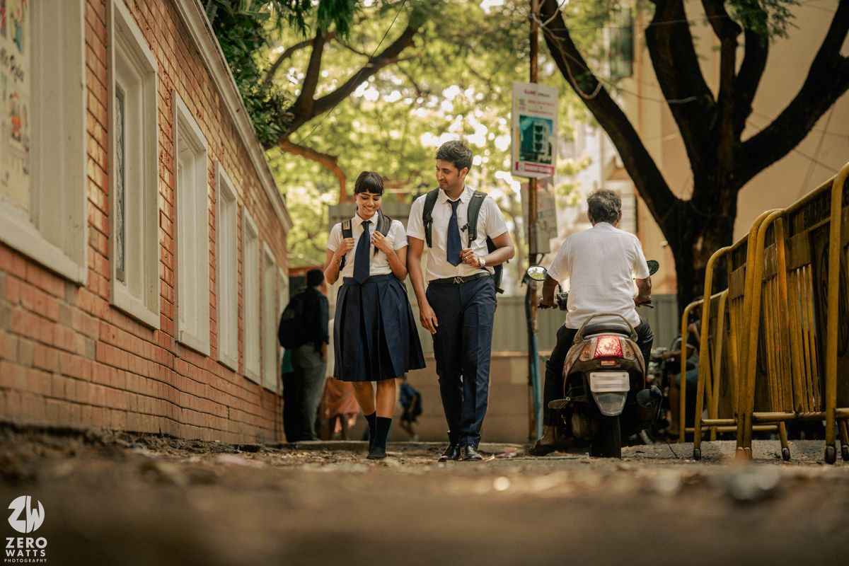 Students walking through a tree-lined pathway outside a school building.
