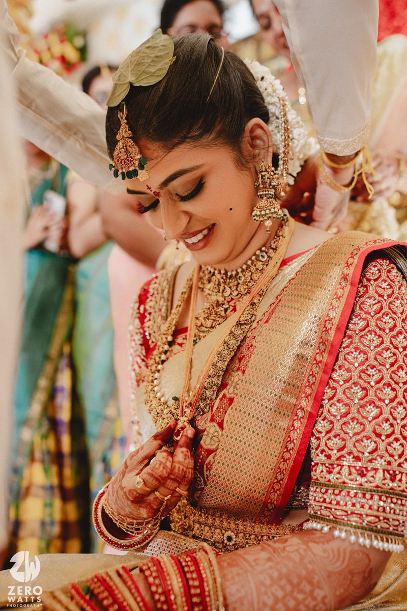Traditional Indian bride in red and gold attire adorned with ornate jewelry and mehndi designs during wedding ceremony.