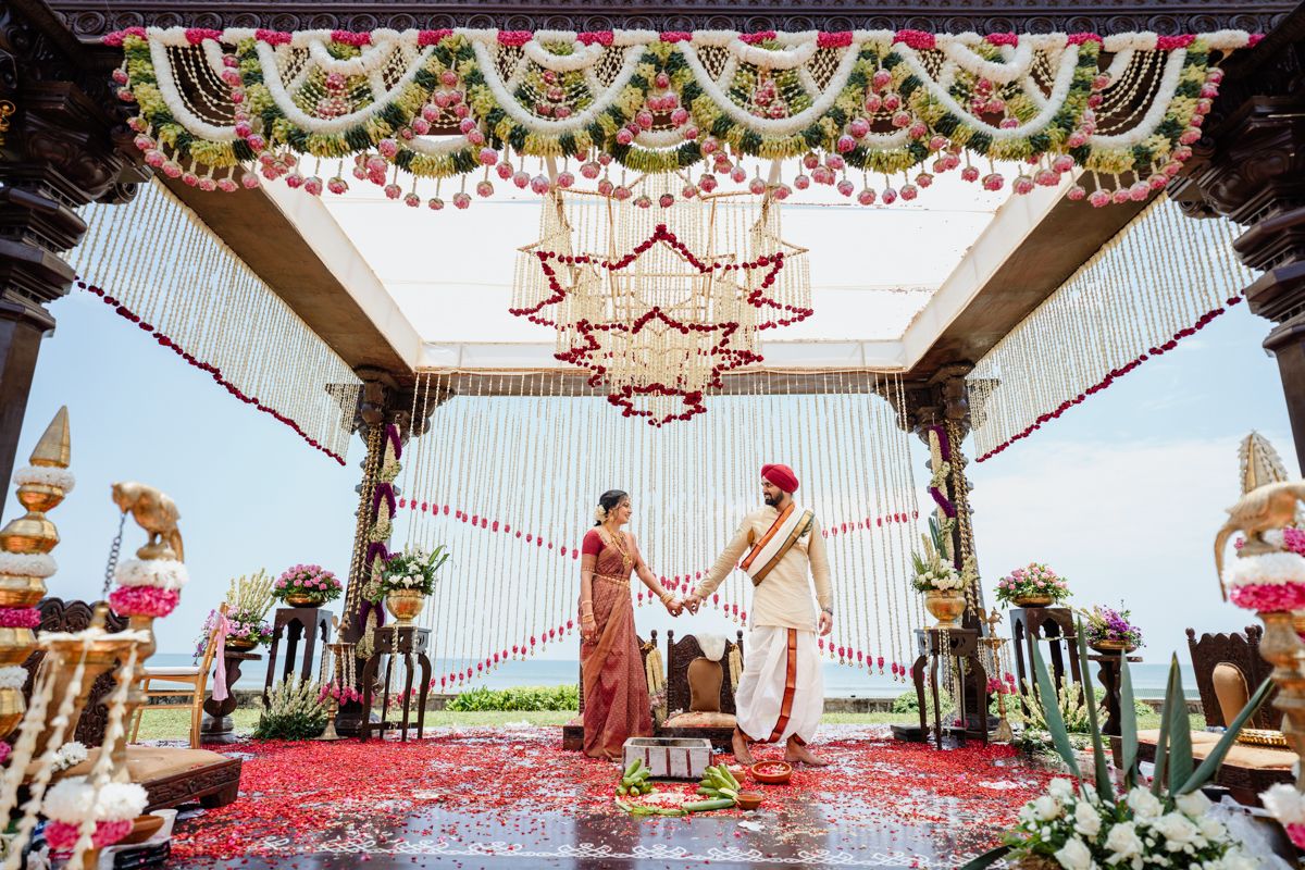 Elegant mandap decorated with floral garlands and traditional Indian wedding decor against a beachside backdrop.