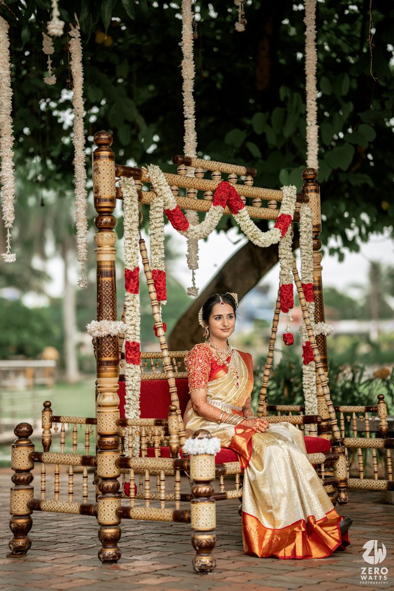 Traditional Indian wedding setup with wooden mandap decorated with red flowers and golden accents in an outdoor setting.