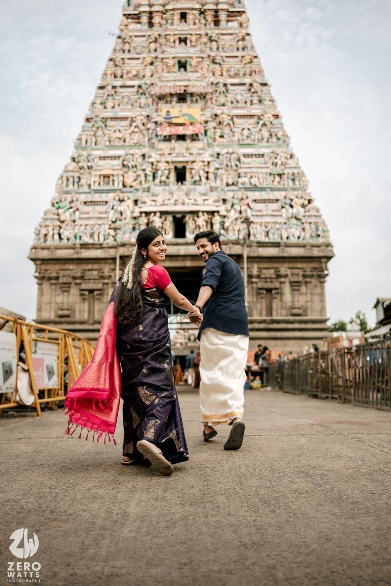 Romantic moment captured in front of ancient temple gopuram with intricate stone carvings and sculptures.