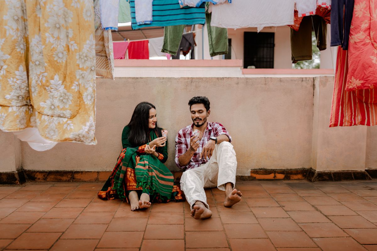 Couple shares intimate moments during an outdoor photo session against weathered walls and colorful decor.