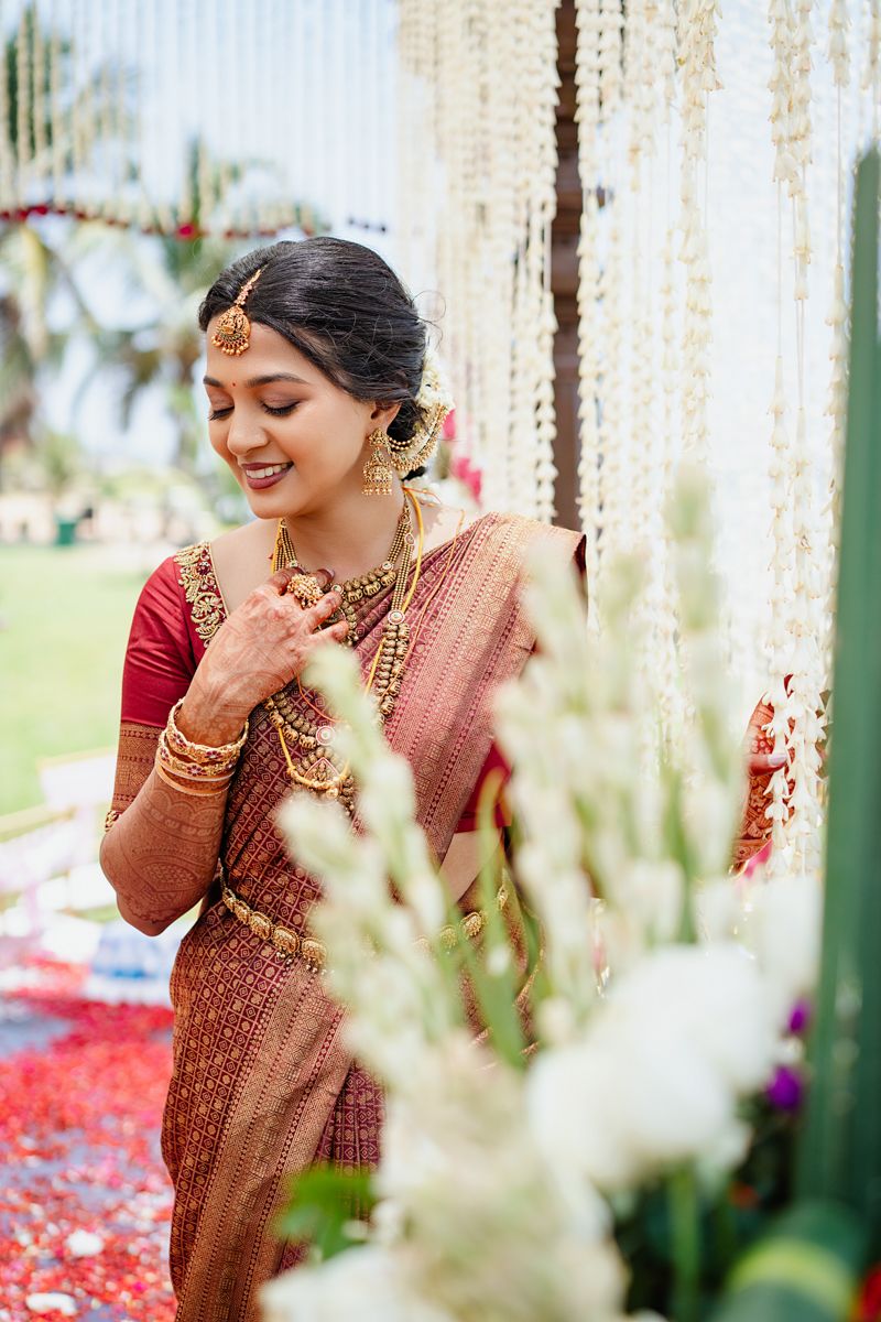 Traditional South Indian wedding decor with white flower strings and crystal curtains creating an elegant backdrop.