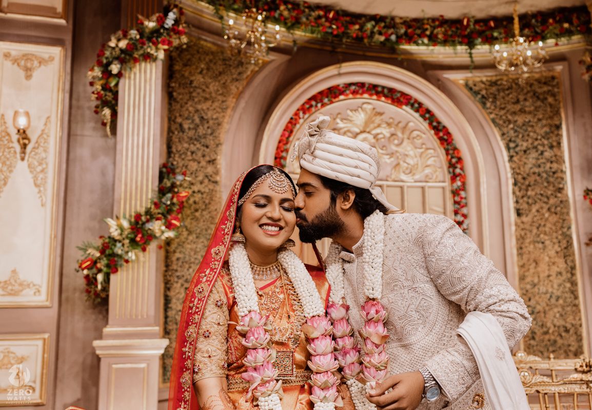 Ornate wedding venue decorated with crystal chandeliers and floral arrangements for a South Asian celebration.