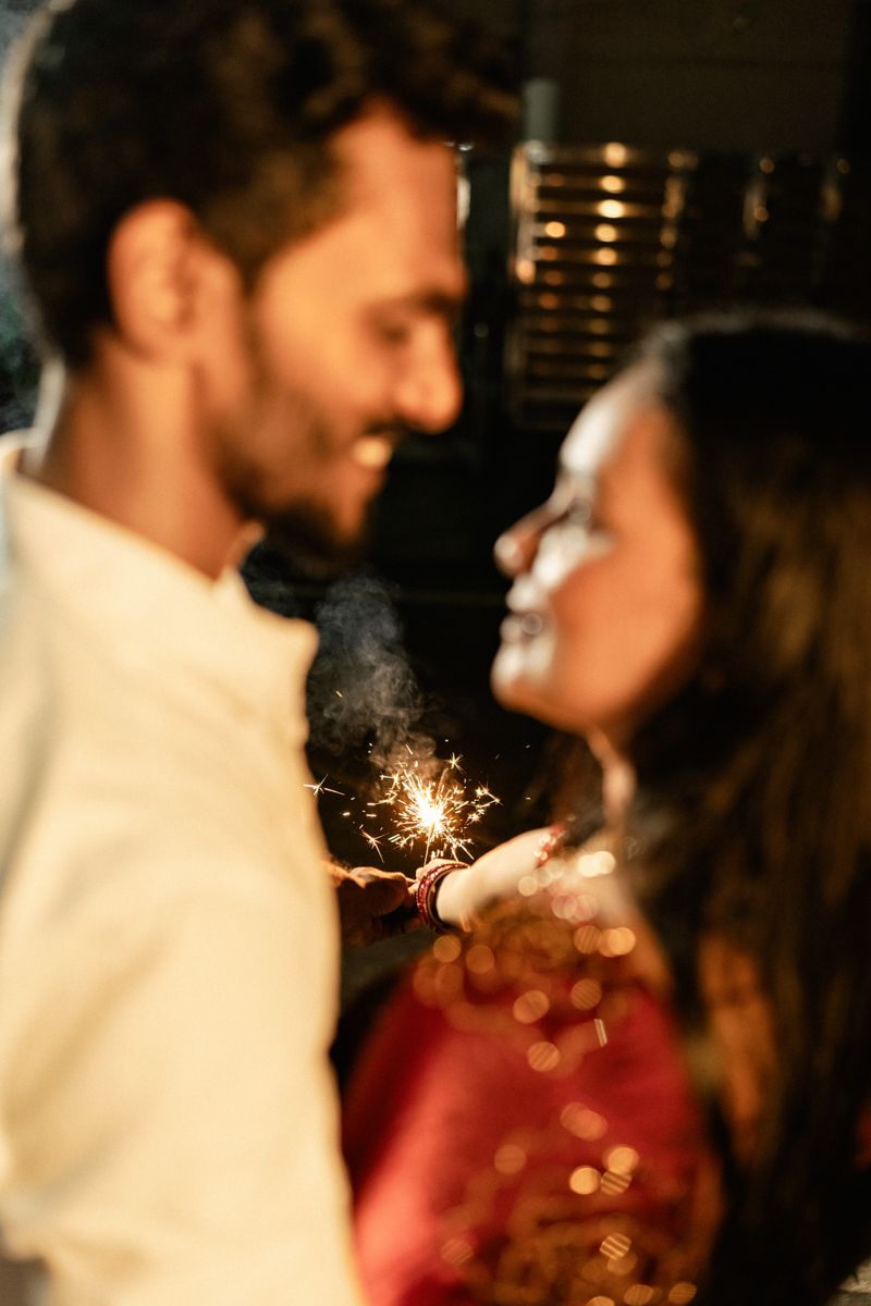 Romantic couple with sparklers creating magical bokeh effects in the dark.