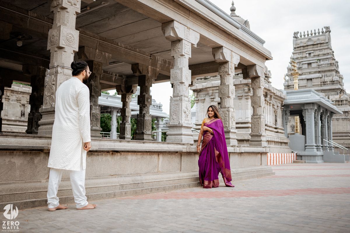 Temple architecture with red and white striped barriers and a couple in traditional attire.