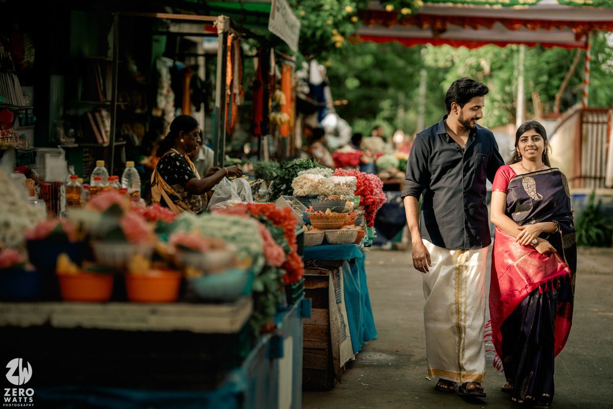 Outdoor temple engagement photoshoot with colorful decorations and greenery in background.