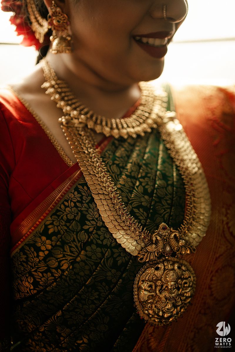 South Indian bride in green Kanjivaram saree wearing layered gold temple jewelry with intricate Lakshmi pendant necklace.