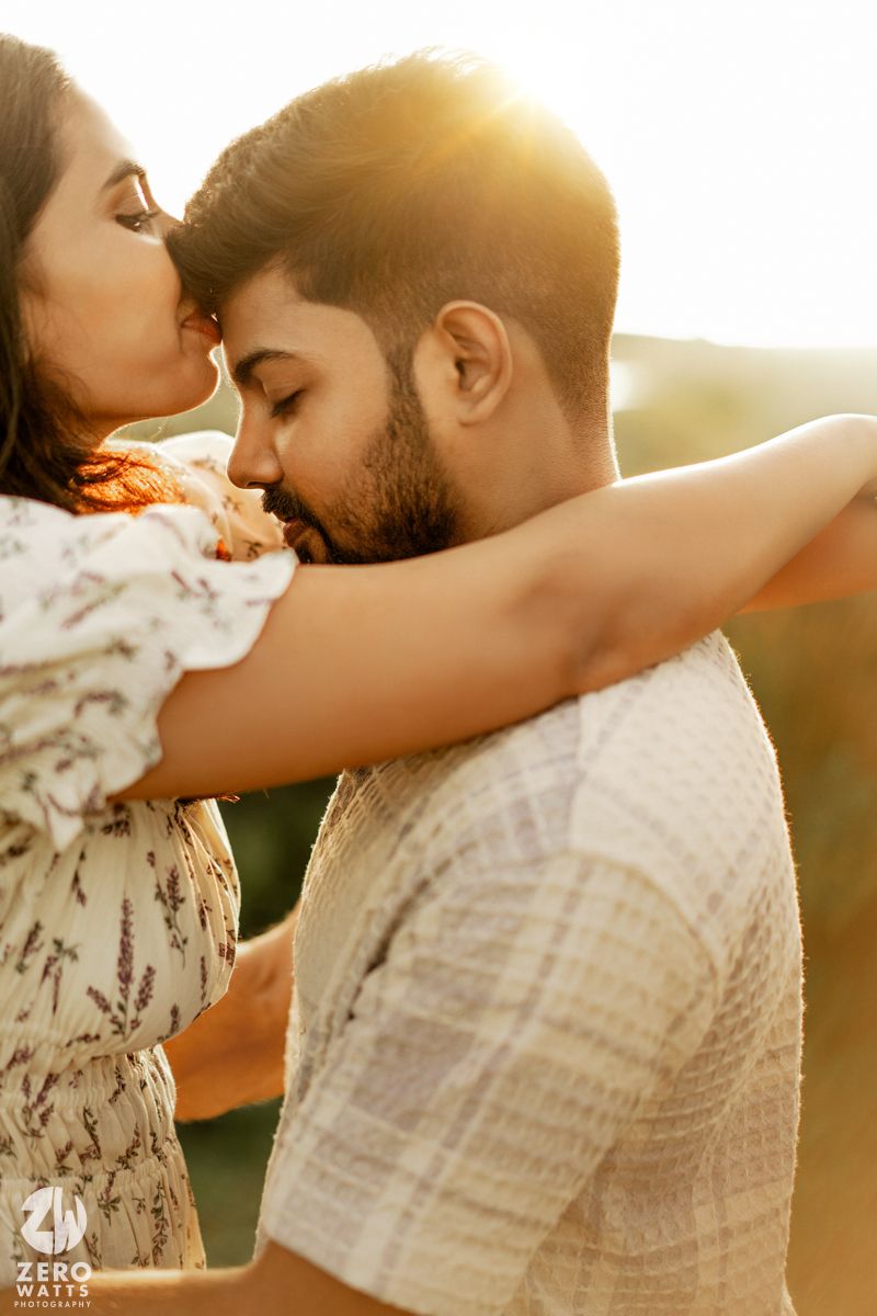 A romantic couple shares an intimate moment at sunset with golden light streaming behind them.