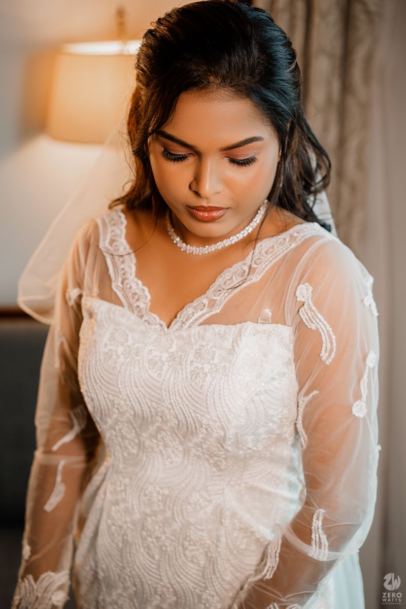 Close-up details of an elegant white lace wedding dress with sheer sleeves and intricate embroidery patterns.