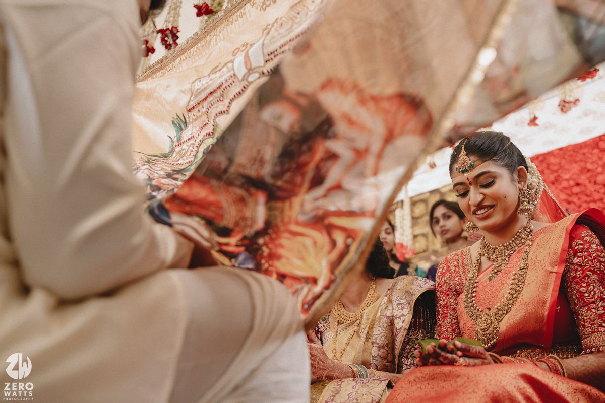 Traditional Indian wedding ceremony with bride wearing red and gold attire and adorned with intricate jewelry.