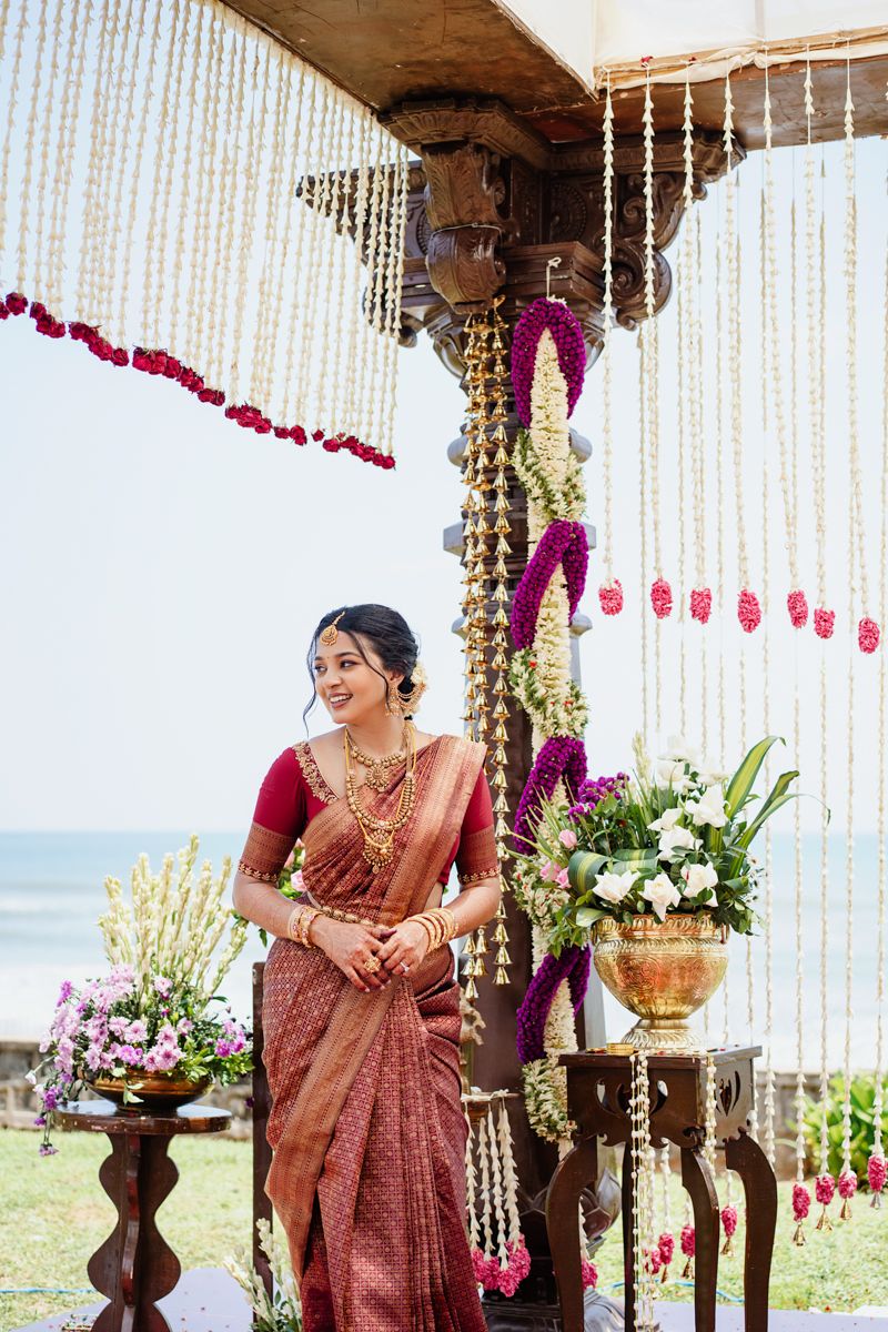 Beachside wedding mandap decorated with white string curtains and floral arrangements.