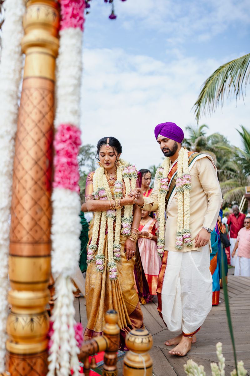 Traditional Indian wedding ceremony setup with ornate gold pillars and pink floral decorations.