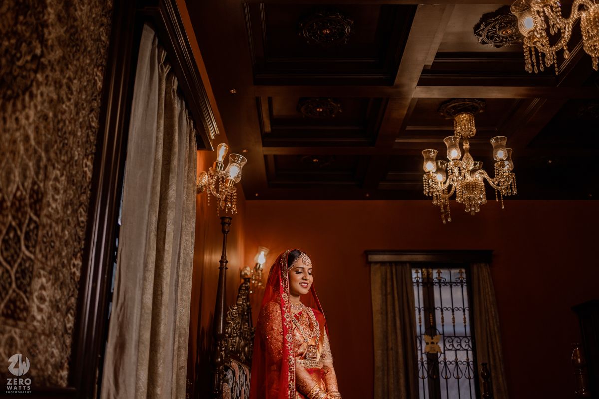 Elegant wedding scene in a luxurious room with ornate chandeliers and rich red and gold decor.