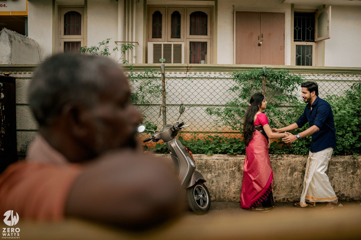 A romantic photoshoot scene captured on a quiet residential street with buildings in background.