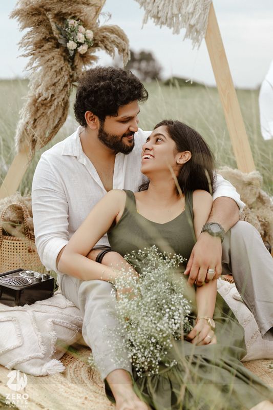 A couple embraces lovingly outdoors surrounded by pampas grass and delicate white baby's breath flowers.