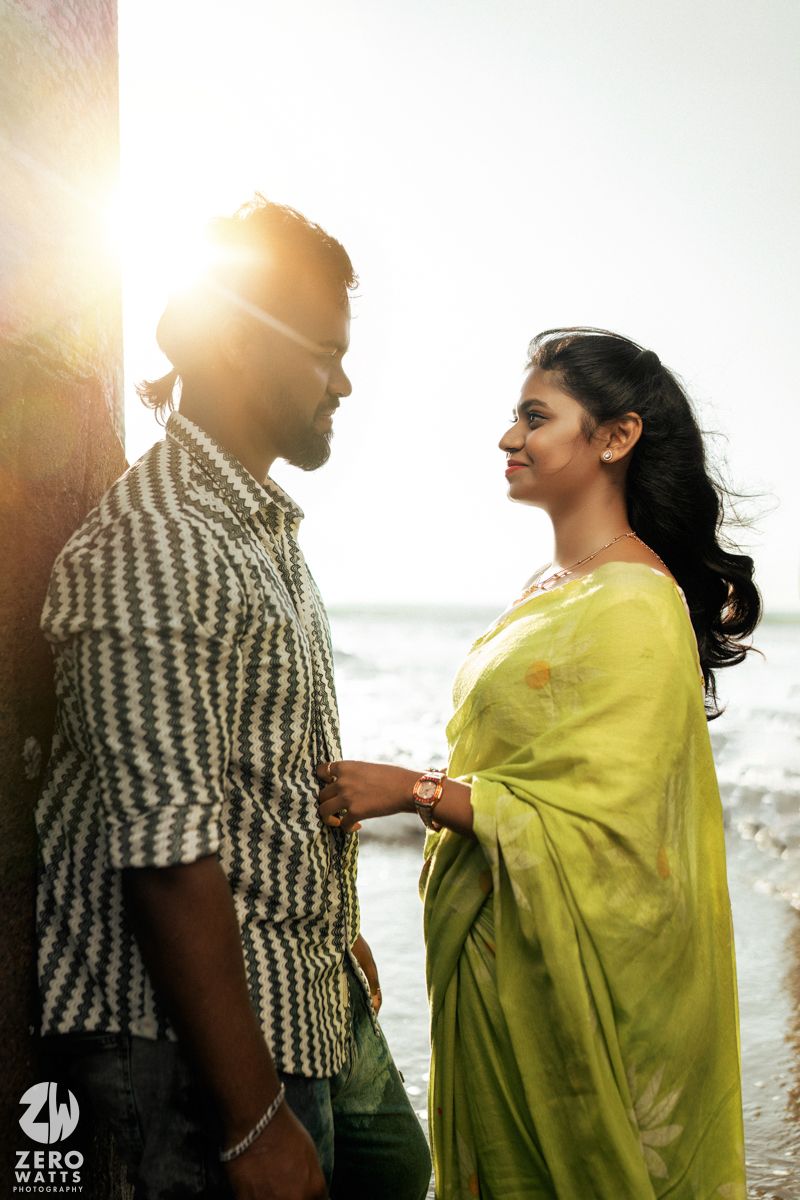 A tender moment between a couple on the beach with sunlight streaming behind them.