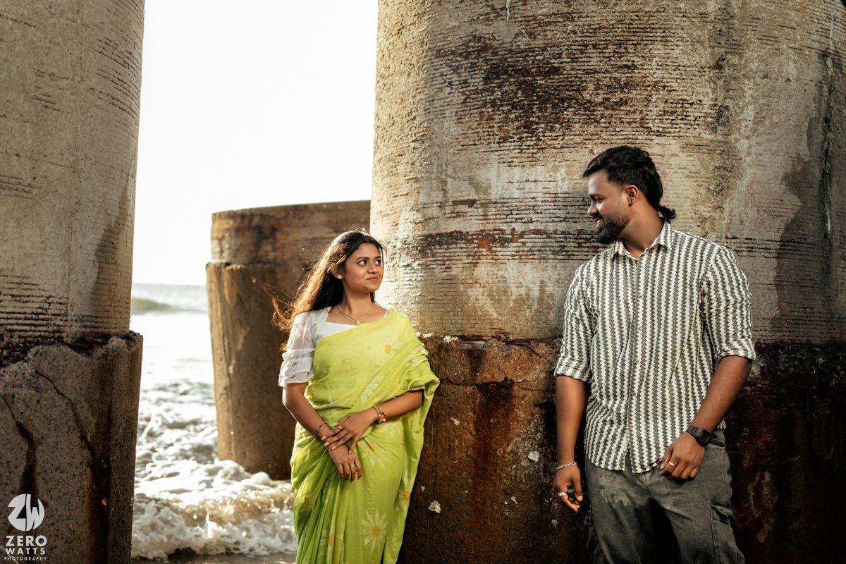 A romantic photoshoot featuring a couple posing between concrete columns.