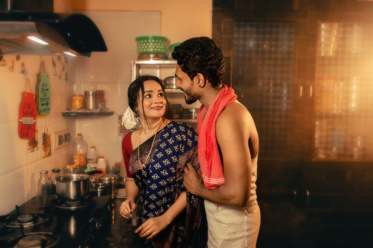 A romantic moment between a couple in a warmly lit kitchen setting.