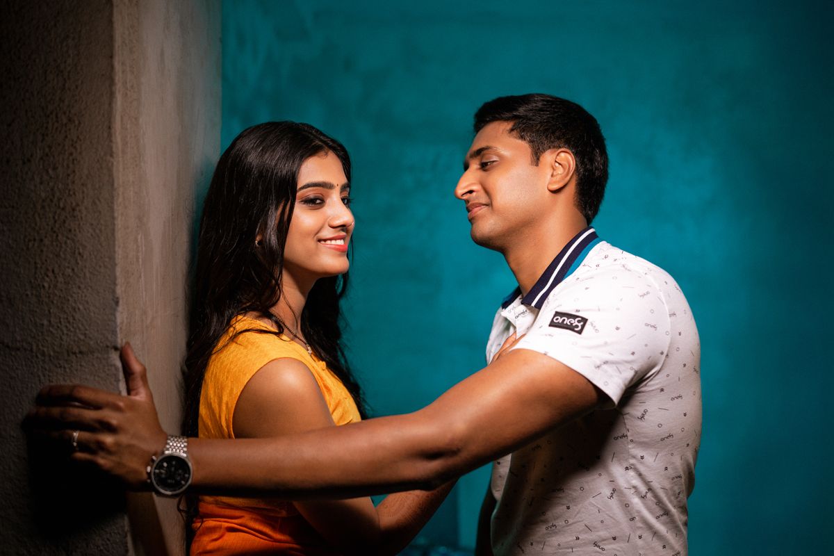 Two people in dramatic lighting against turquoise background showing intense emotional moment.