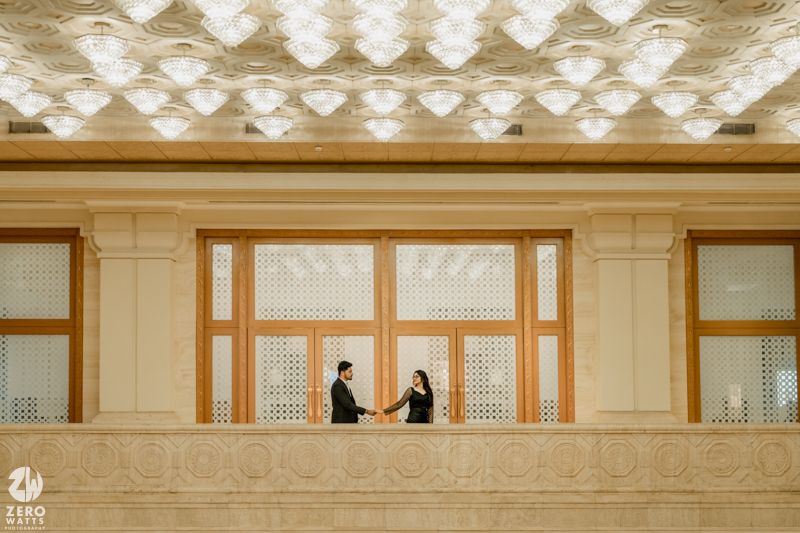 Silhouetted figures against geometric ceiling pattern in modern architectural space.