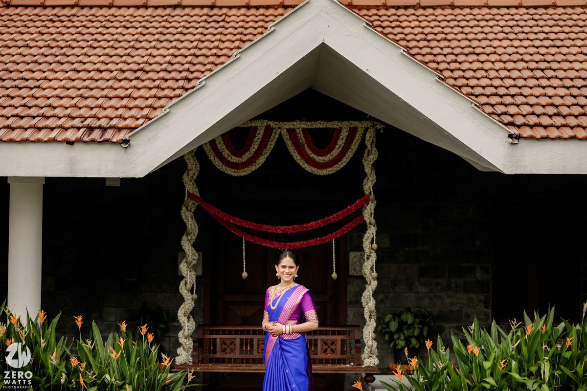 Traditional Kerala-style architecture with red tiled roofs and ornate wooden pillars decorated for a cultural celebration.