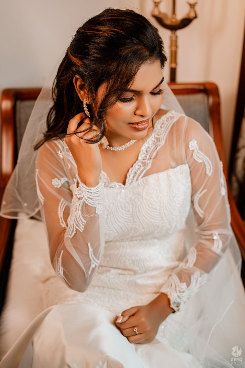 Close-up details of an intricate white wedding dress with delicate lace patterns and sheer sleeves.