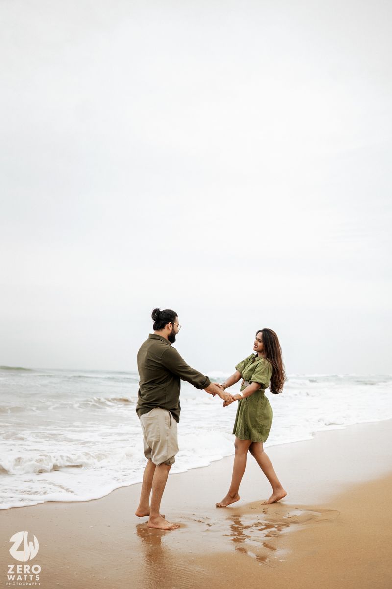 People dance and twirl together on a foggy beach with waves crashing in the background.