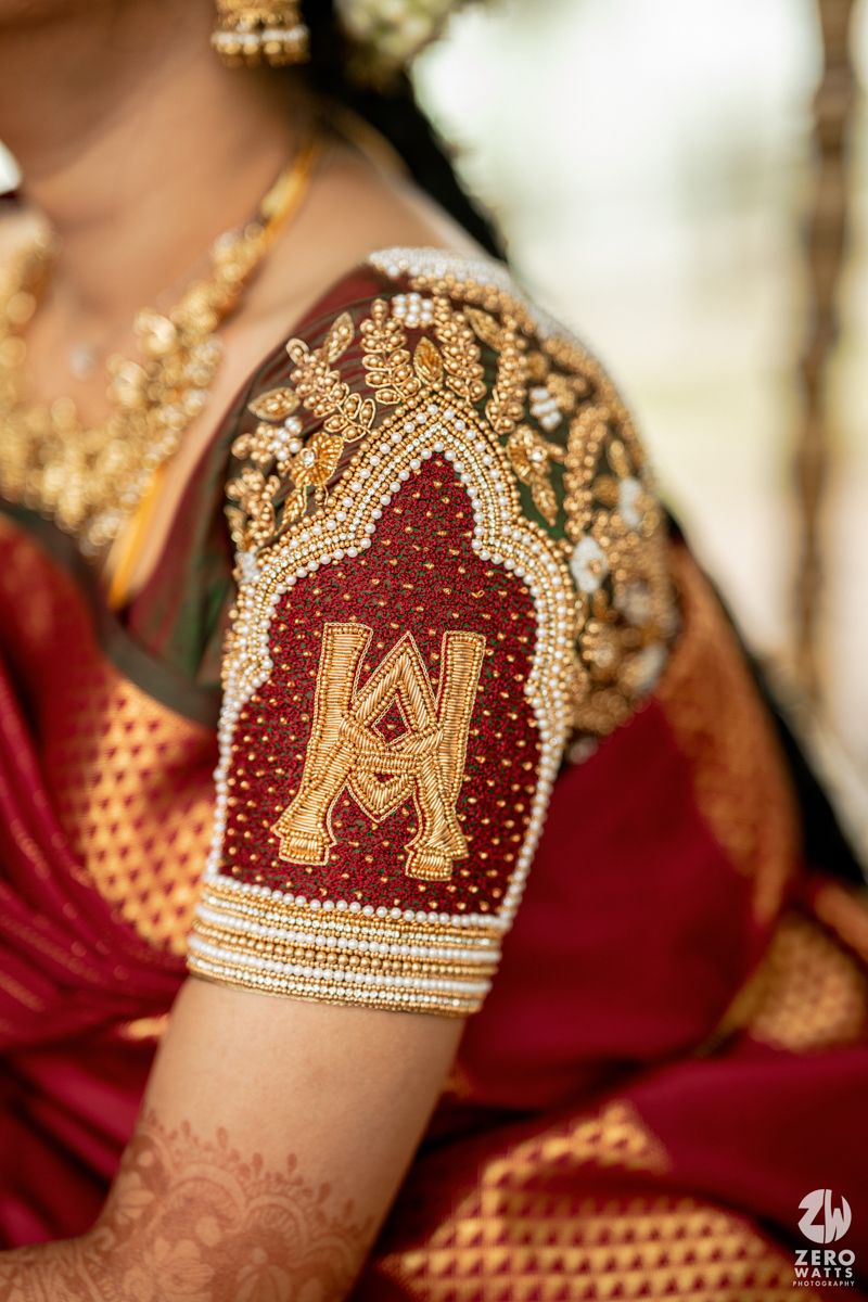 Detailed embroidery work on a red wedding blouse featuring intricate gold and maroon beadwork patterns.