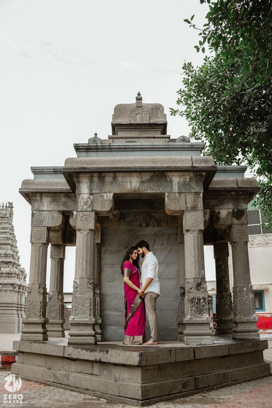 A romantic moment captured in a stone temple mandap with carved pillars and traditional architecture.
