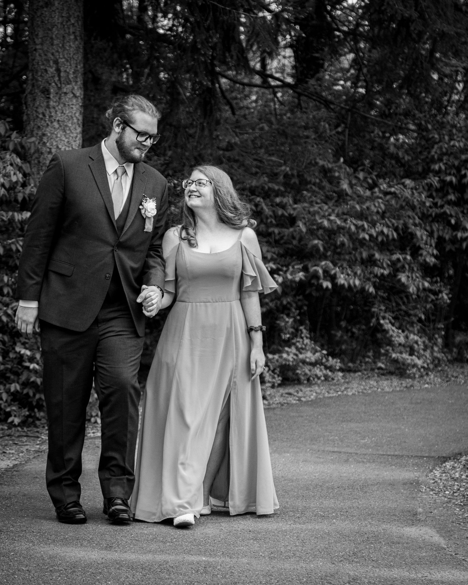 Black and white portrait of couple walking together on garden path.